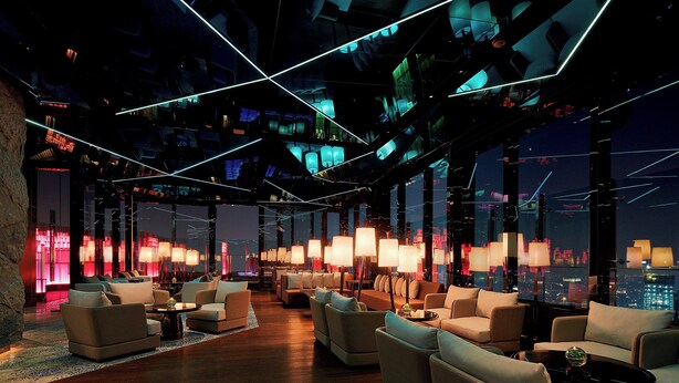 Un'elegante area lounge con divani e tavolini, ampie finestre e vista sulla città.