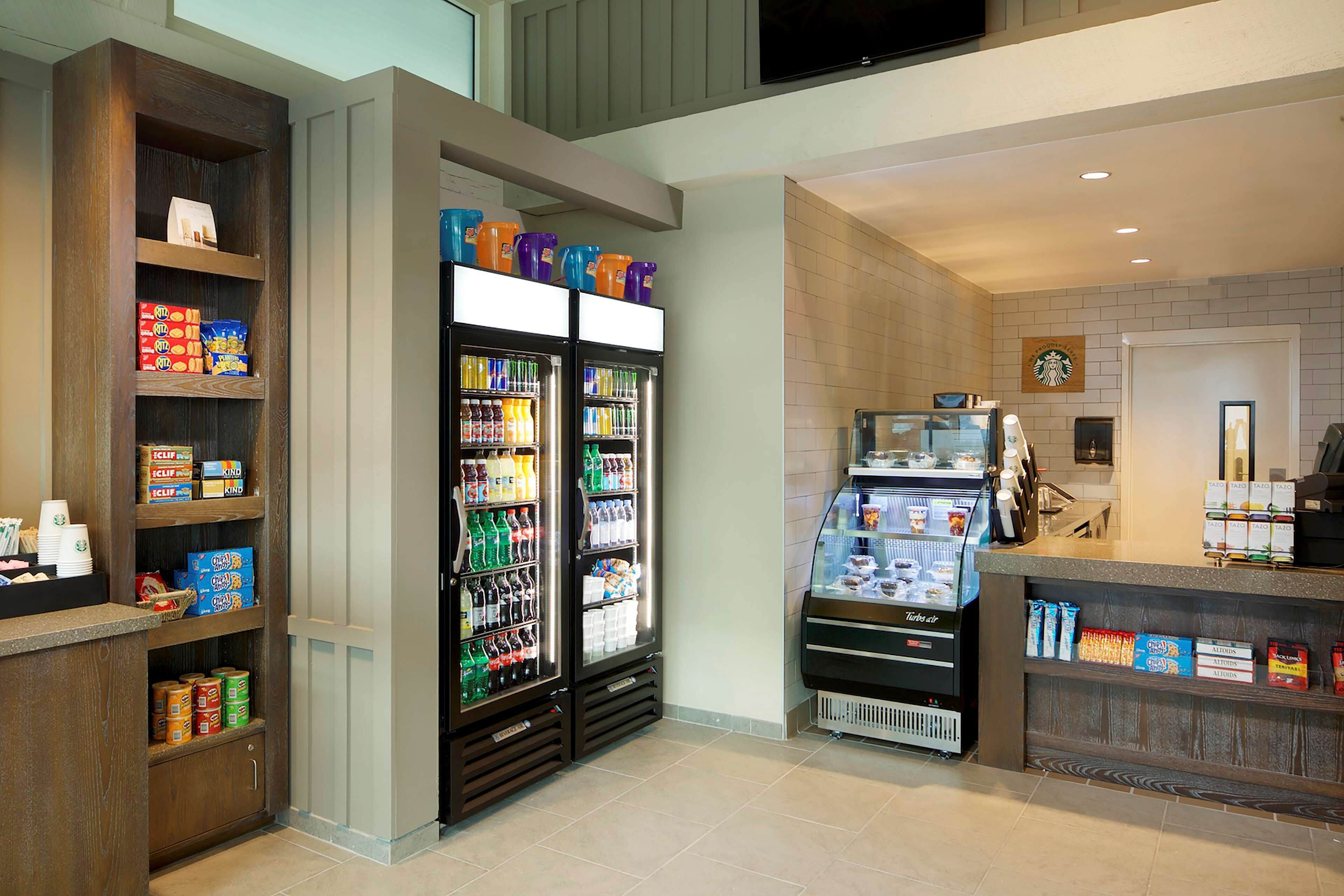 A hotel lobby with a self-service beverage station, snack dispensers, and a Starbucks coffee machine.