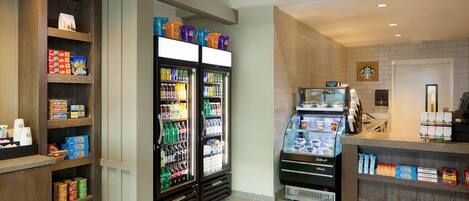A hotel lobby with a self-service beverage station, snack dispensers, and a Starbucks coffee machine.