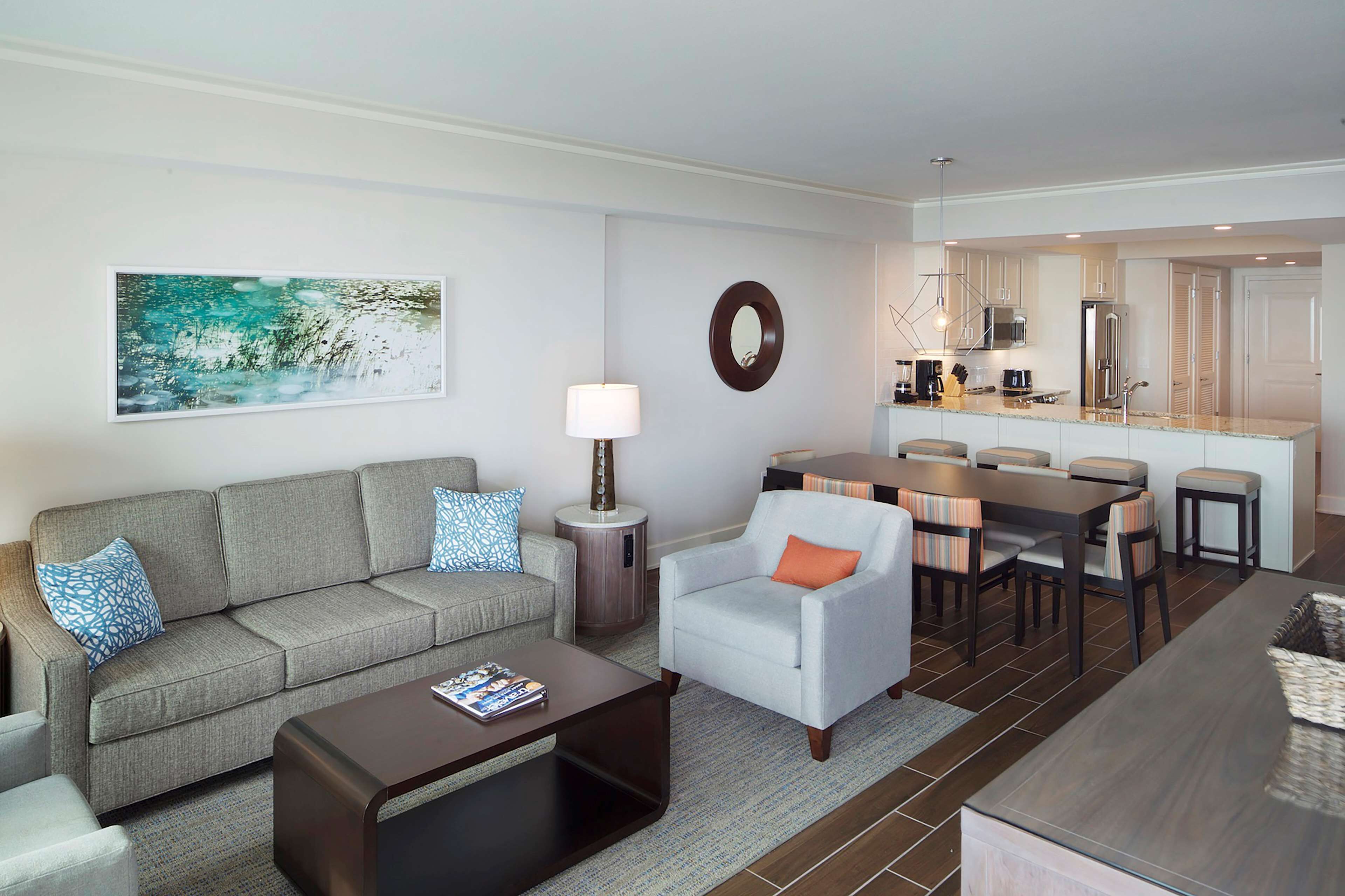 Un salon moderne comprenant un canapé, un fauteuil, une table basse et un coin repas avec des chaises et une table.