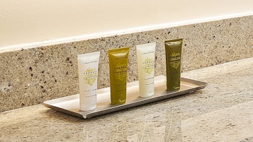 Four tubes of Verbena and Lavender body lotion on a tray against a speckled countertop.
