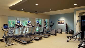 A gym with treadmills, a rowing machine, and dumbbells.