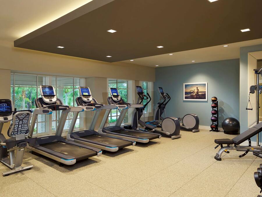 A gym with treadmills, a rowing machine, and dumbbells.