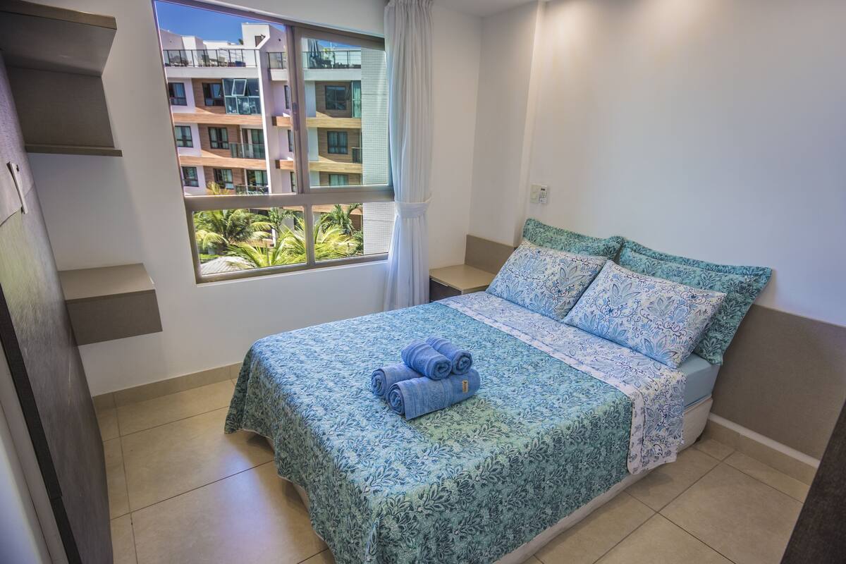 Ein Schlafzimmer mit einem Bett, einem Fenster und Blick auf Gebäude.