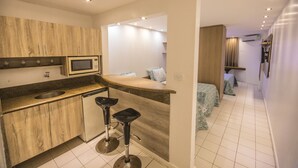 Una cocina moderna con armarios de madera, un microondas, un lavamanos y dos taburetes de bar.