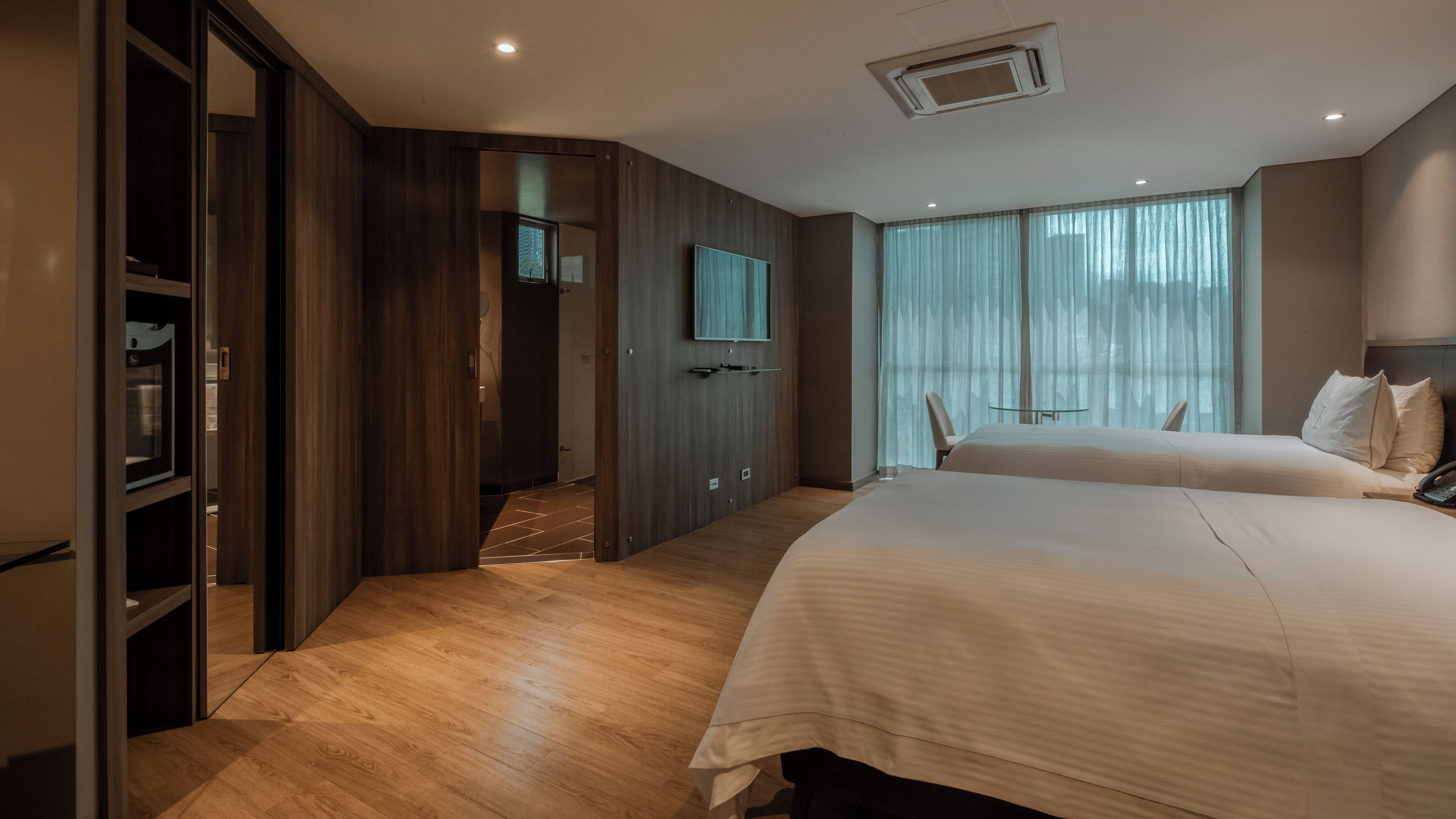Una habitación de hotel moderna con una cama grande, un televisor montado en la pared y un vestidor.