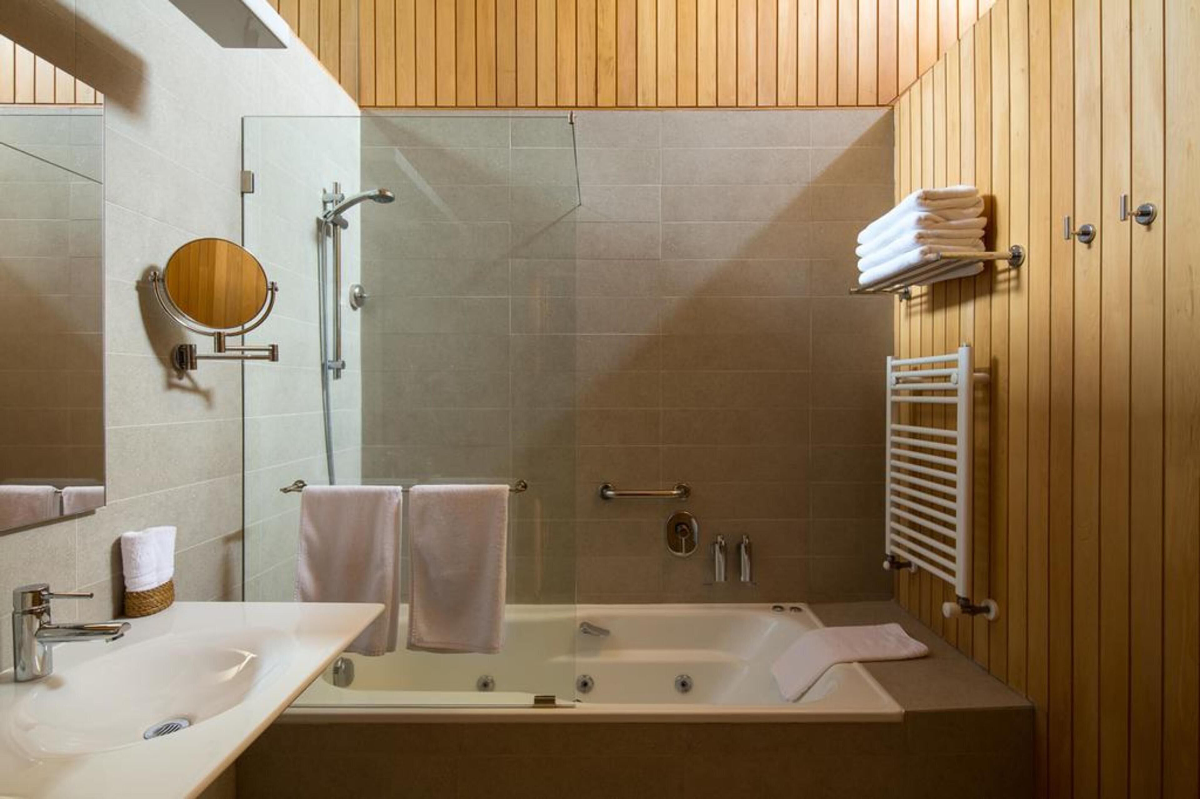 Un baño moderno con un tocador de madera, cabina de ducha de vidrio y bañera integrada.