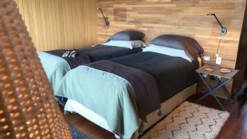 Ein Schlafzimmer mit zwei Betten, Holzwandverkleidung, einem kleinen Tisch und einem gemusterten Teppich.