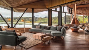 A spacious living area with a large sectional sofa, a wooden coffee table, and a fireplace. - Refugia Chiloé (Castro)