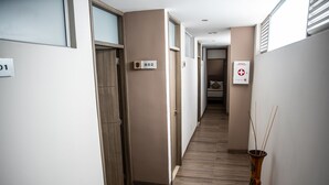 Um corredor com piso de madeira, um vaso com galhos, e portas numeradas 302 e 301.