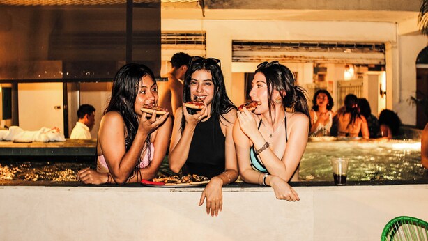 A poolside area with people relaxing and eating. - Hotel Petén Express - Hostel (Flores)