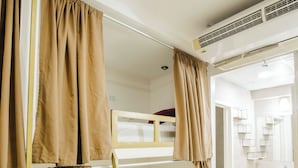 A bunk bed room with a ladder, beige curtains, and a bathroom with a mirror and sink.