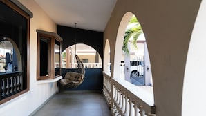 Un couloir avec une chaise suspendue, une balustrade et une vue sur l’extérieur.