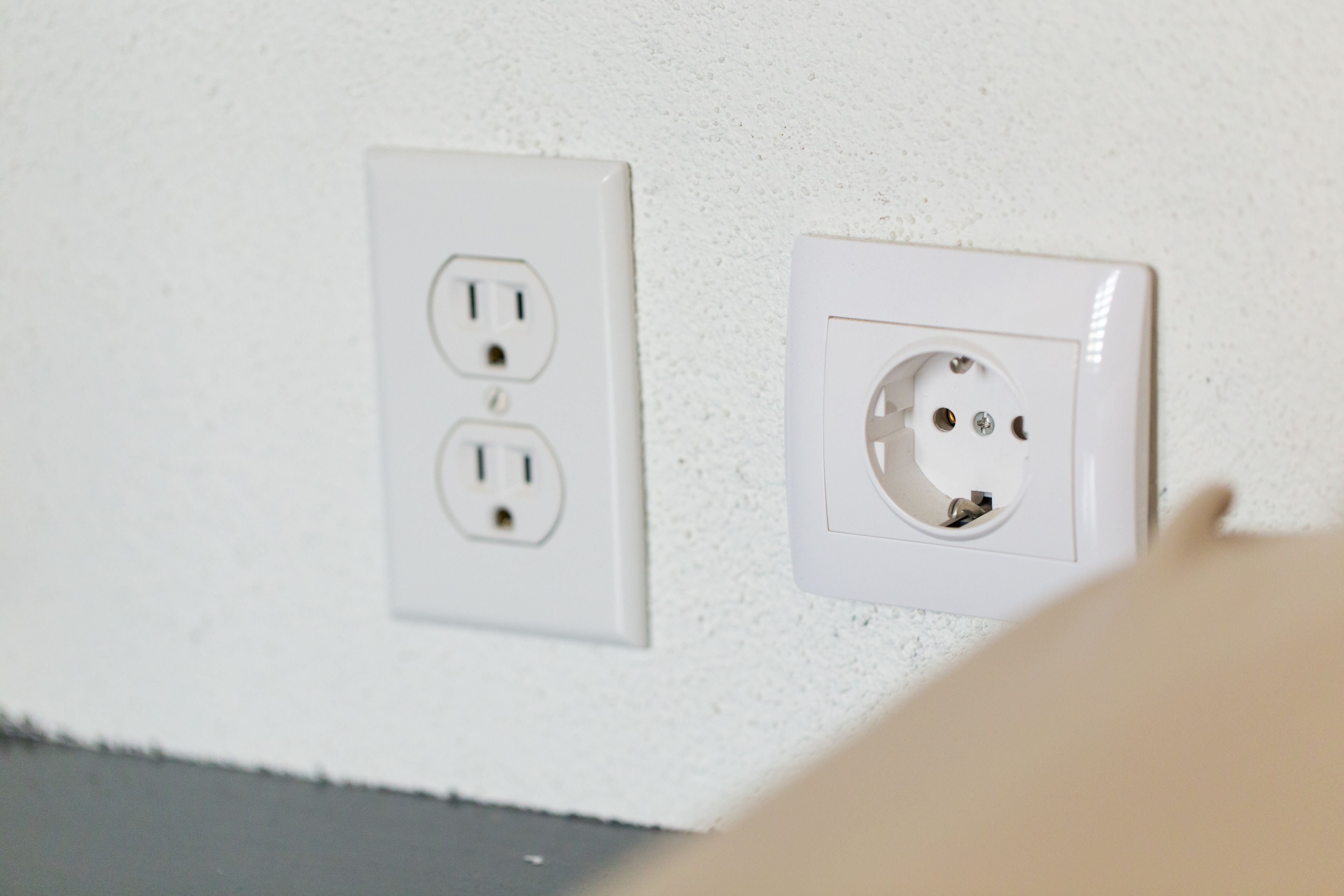 Two white electrical outlets on a textured wall.