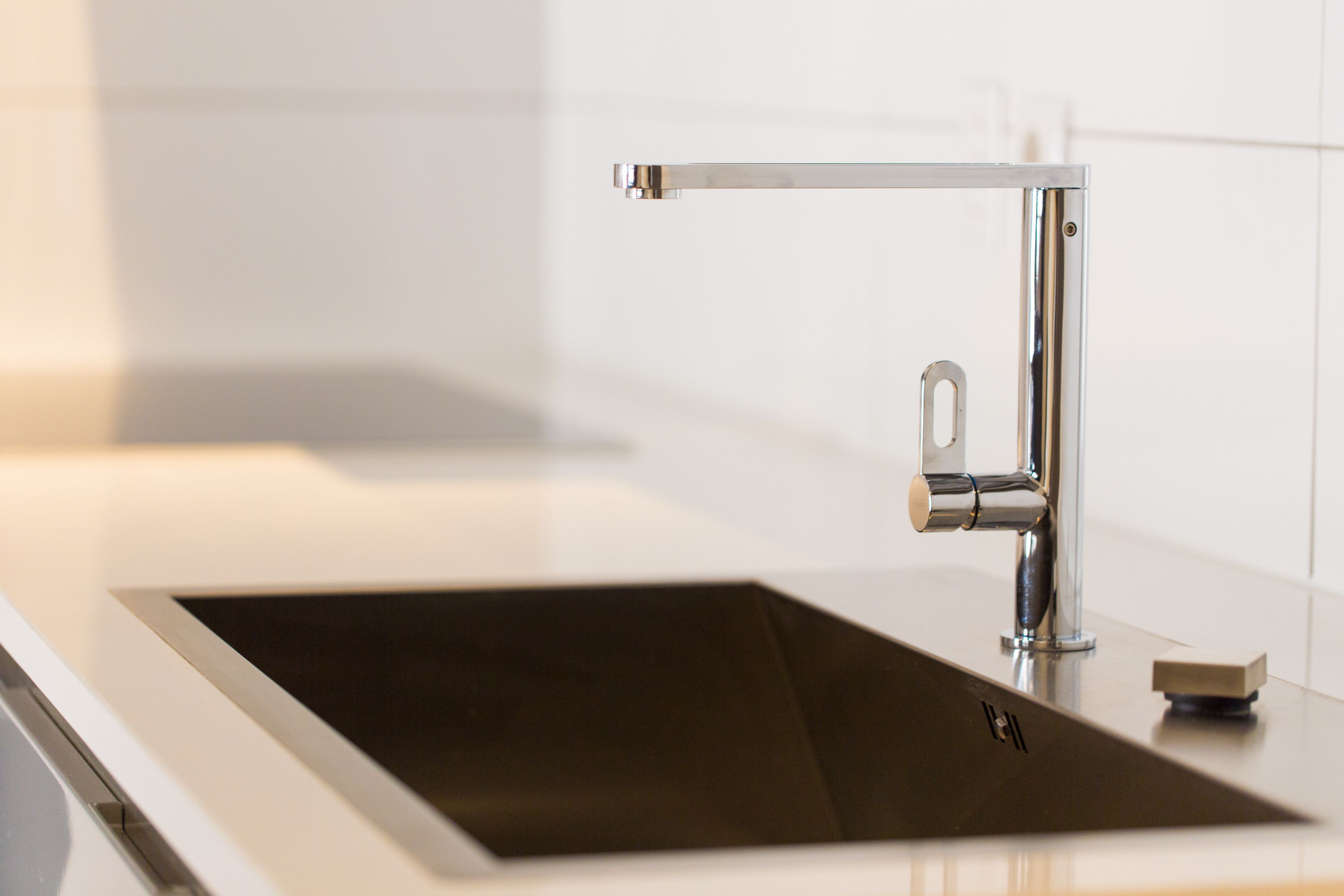 Una cocina moderna con un lavamanos de acero inoxidable, un grifo y un jabonera.