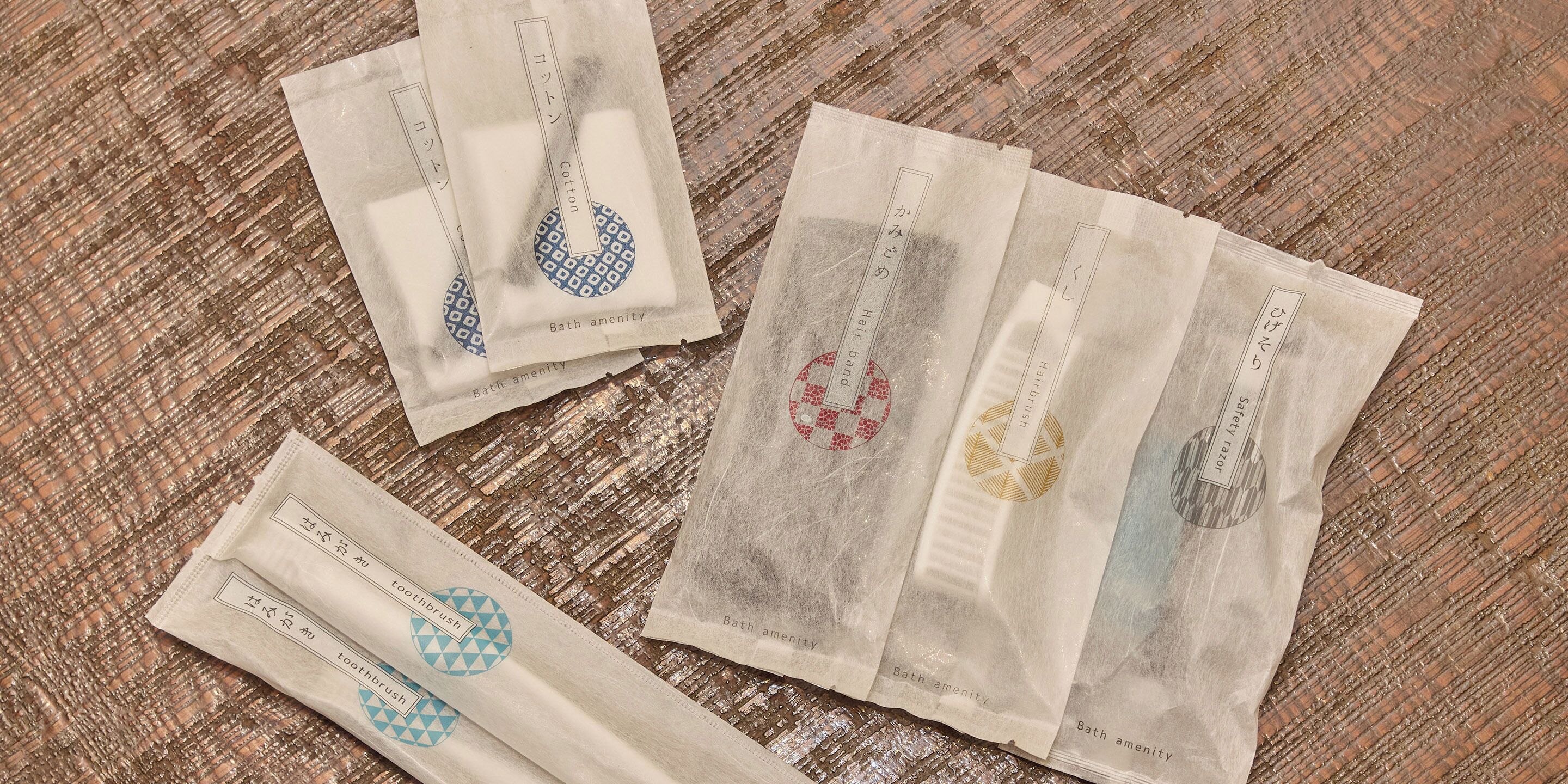 Four packages of bath amenities on a wooden surface.