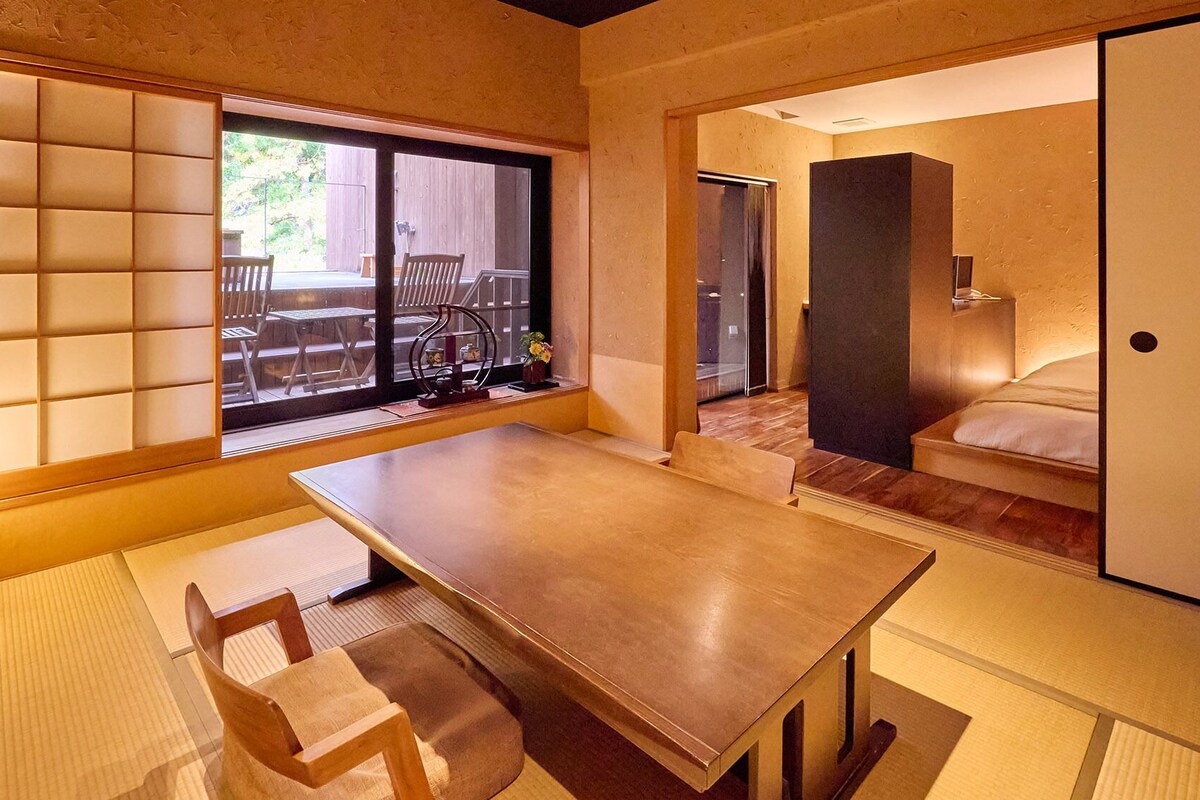 A traditional Japanese-style room with tatami flooring, a low table, and sliding doors leading to a balcony.