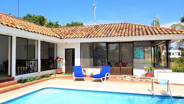 Una casa moderna con piscina, ventanas amplias y techo de tejas.