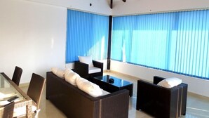 Una habitación moderna con una mesa de vidrio, muebles de mimbre y un ventilador de techo.