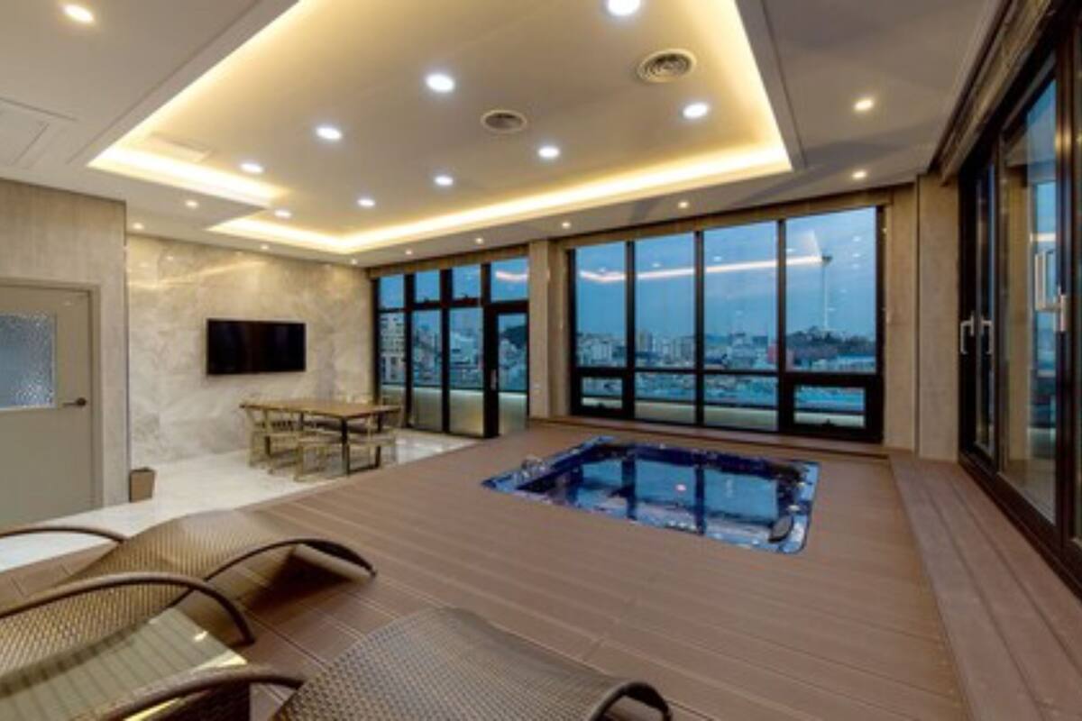A spacious room with a hot tub, a dining area, and large windows offering a city view.