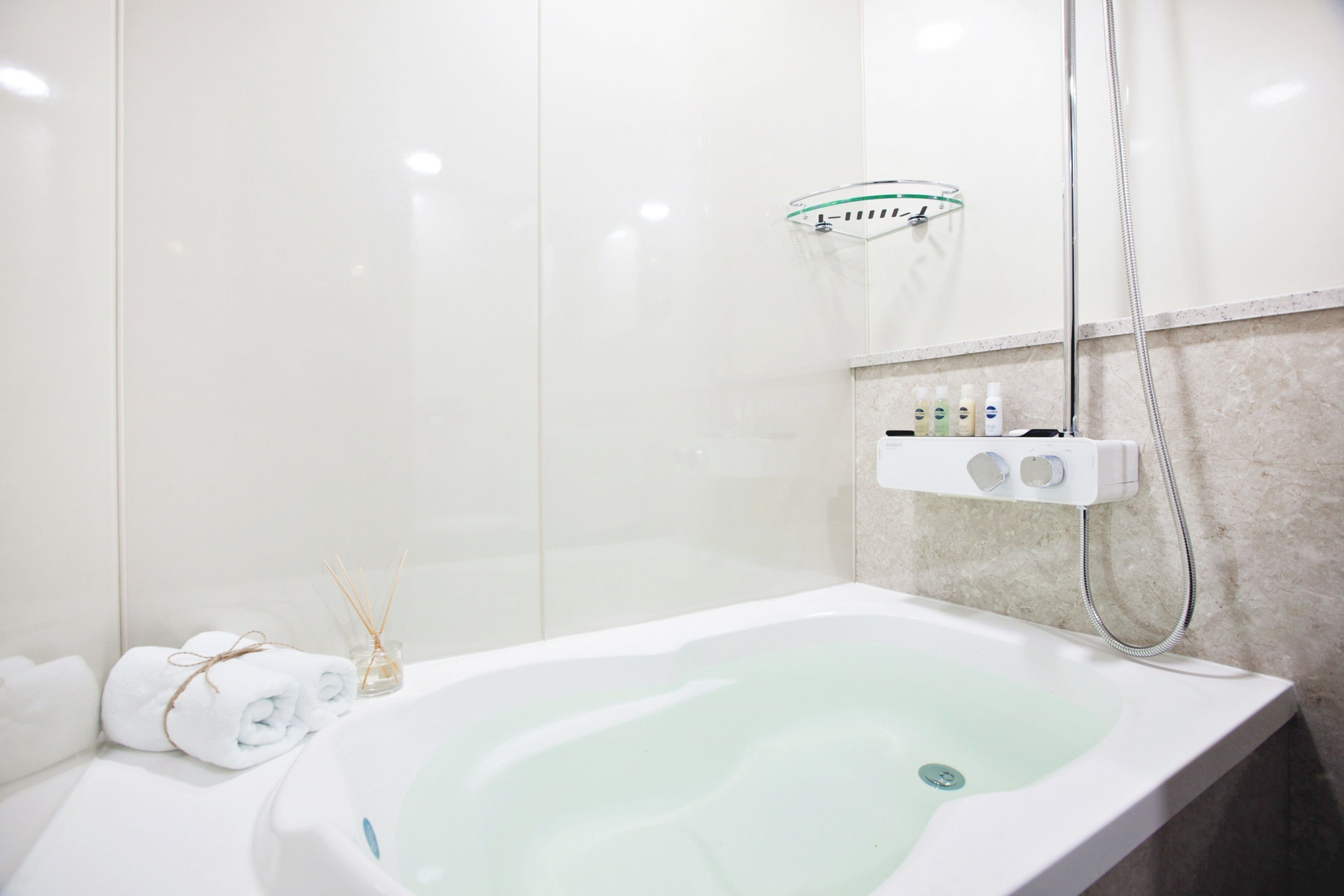 Une salle de bain moderne avec une baignoire sur pieds, une douche à parois de verre et un distributeur de savon fixé au mur.