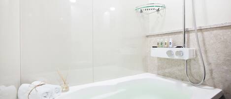 Une salle de bain moderne avec une baignoire sur pieds, une douche à parois de verre et un distributeur de savon fixé au mur.