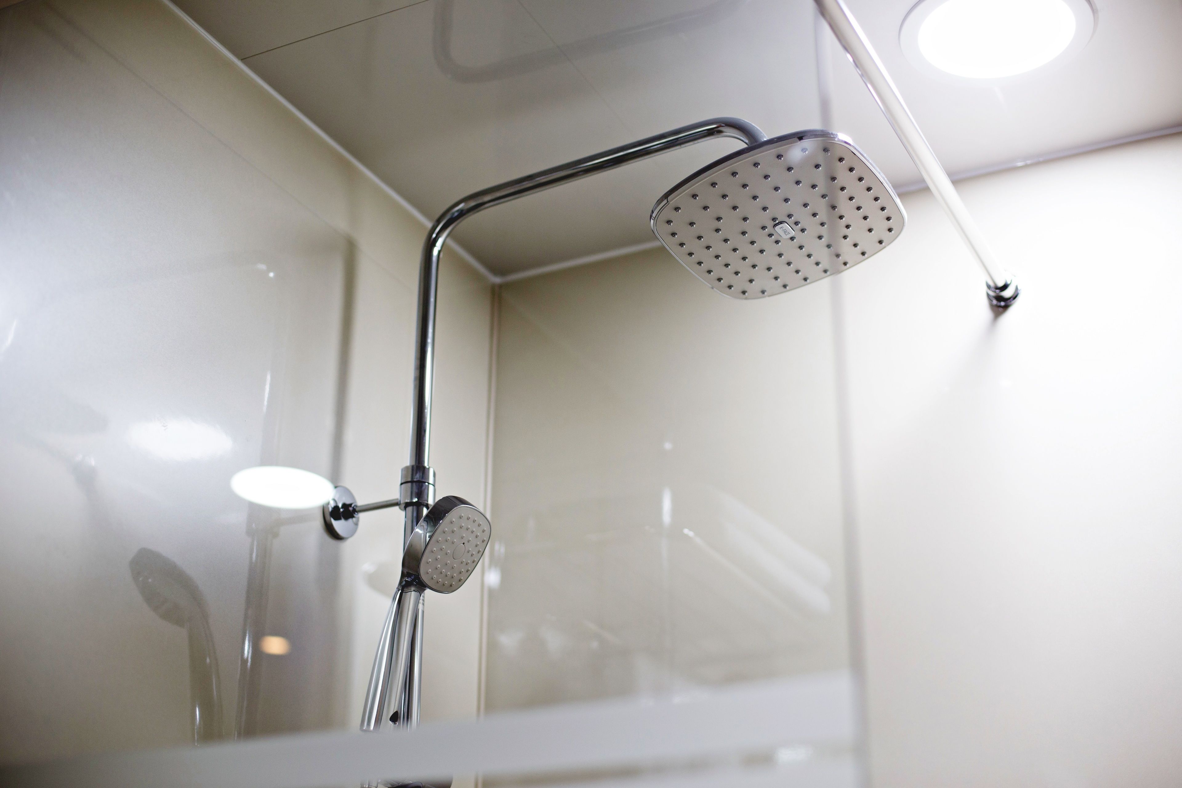 A showerhead with a curved handle and a round spout, mounted on a chrome fixture.