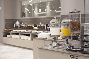 A breakfast bar with coffee and juice dispensers, a variety of breakfast items, and a tiled backsplash. - GNB Hotel (Busan)