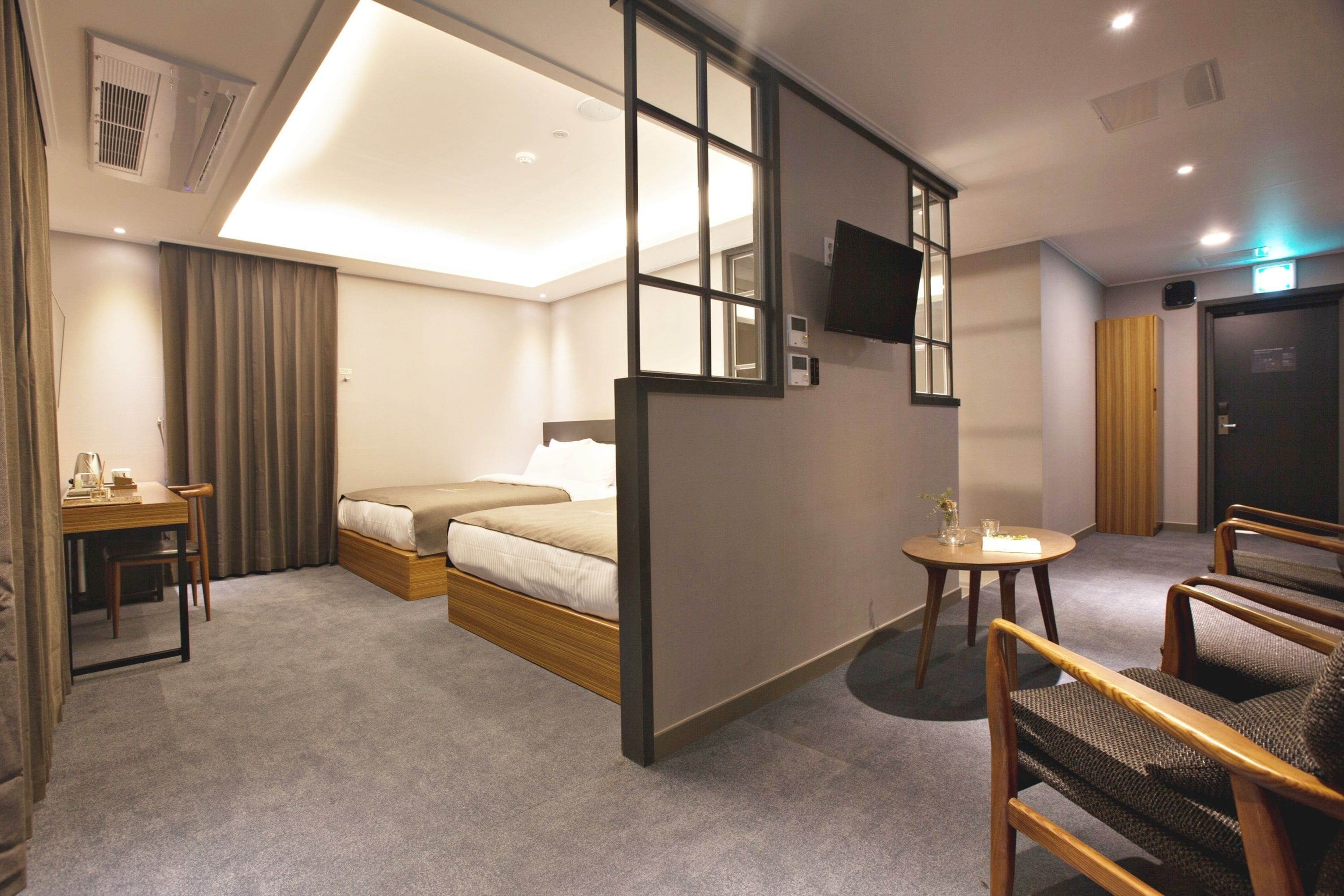 A hotel room with a bed, a desk, a chair, a small table, and a TV.