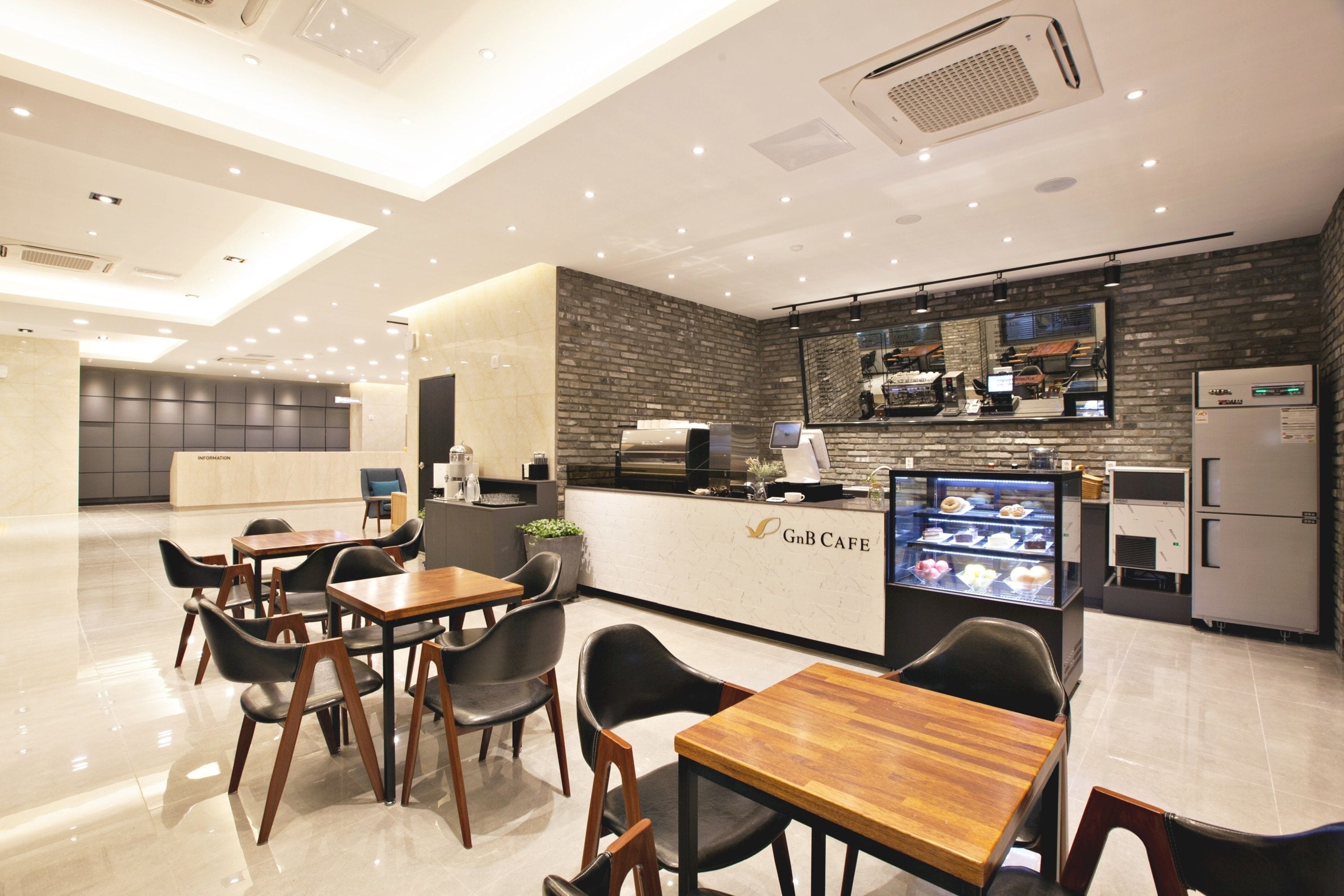 A modern cafe with a counter, seating area, and a display case.
