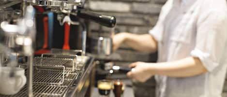 A barista at an espresso machine, preparing coffee.