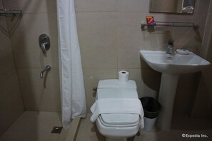 A bathroom with a toilet, a sink, a shower, and a trash bin.