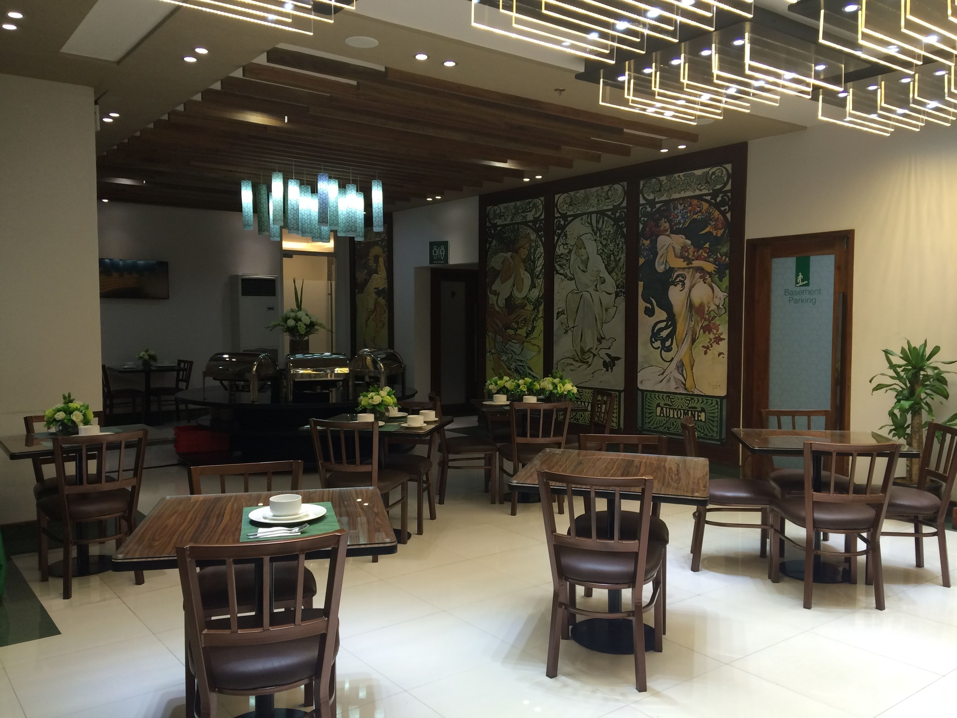 A restaurant with wooden tables and chairs, a modern ceiling design, and decorative wall art.