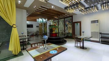 A hotel lobby with a central round table, multiple seating areas, and a decorative fountain.