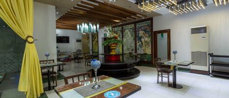 A hotel lobby with a central round table, multiple seating areas, and a decorative fountain.