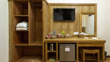 Un mueble de madera con estantes, un televisor, un espejo, un refrigerador y una pequeña mesa con diversos objetos.