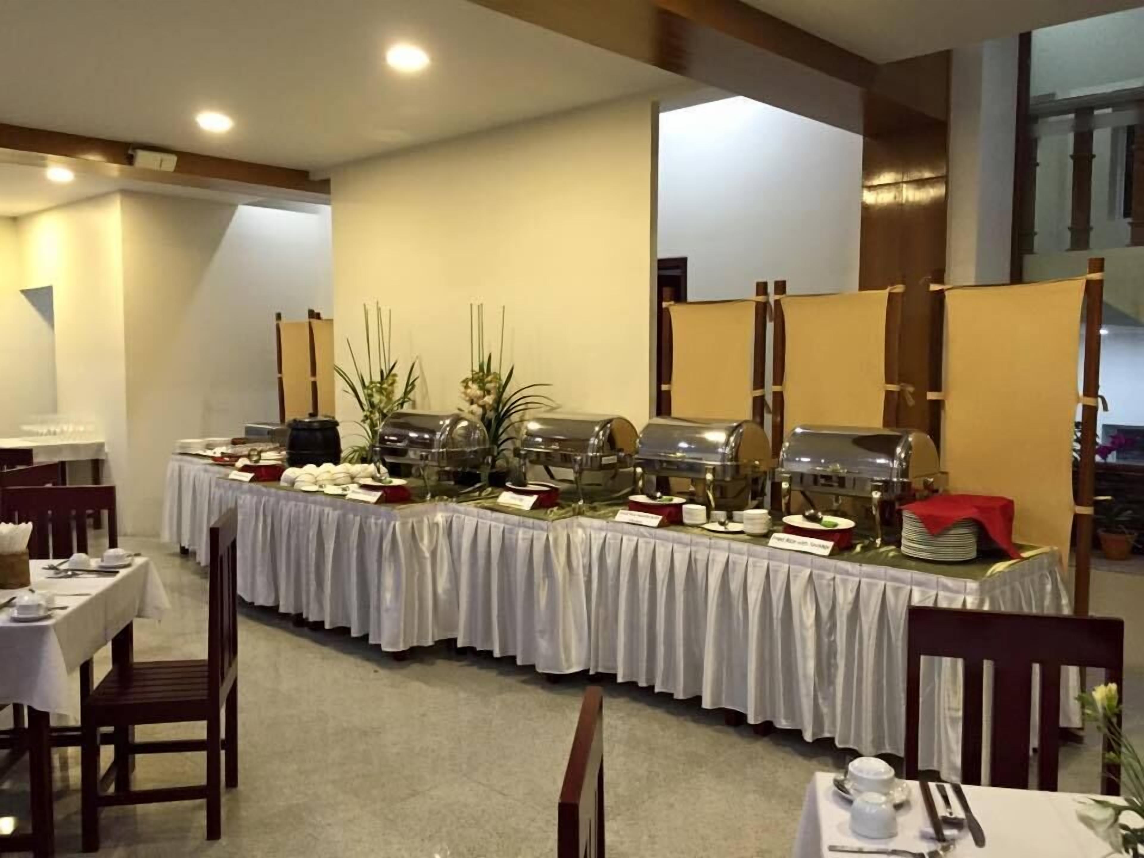 A buffet setup with multiple food stations, tables, and chairs in a dining area.