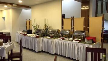 A buffet setup with multiple food stations, tables, and chairs in a dining area.