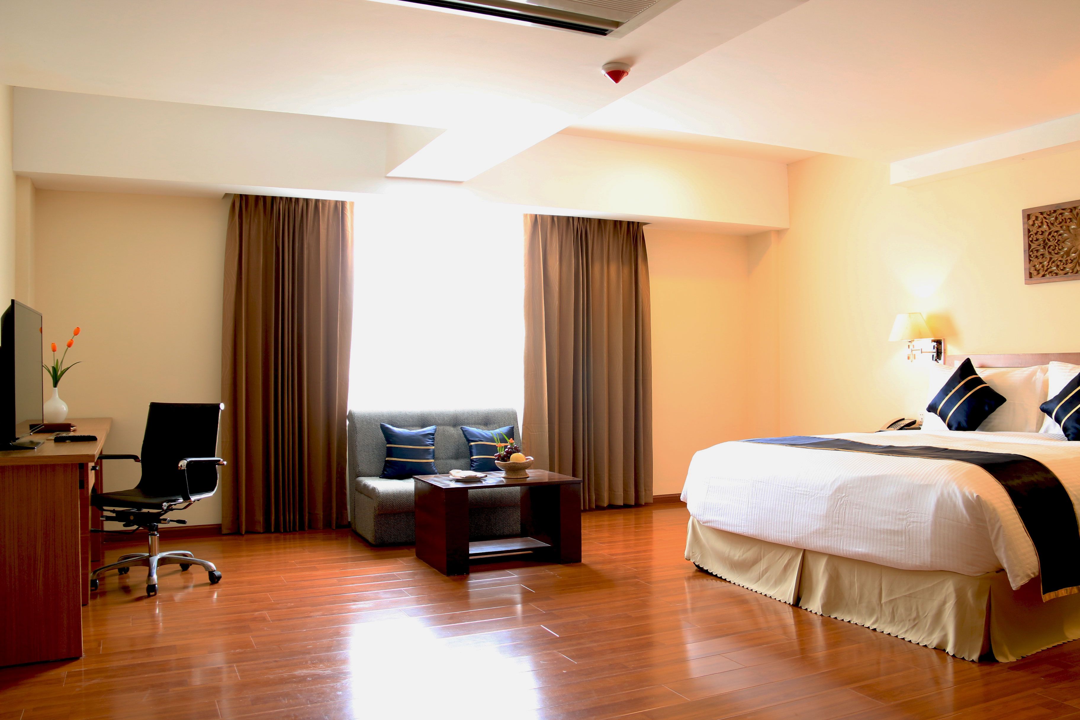 A hotel room with a bed, a desk, a chair, a sofa, and a small table.