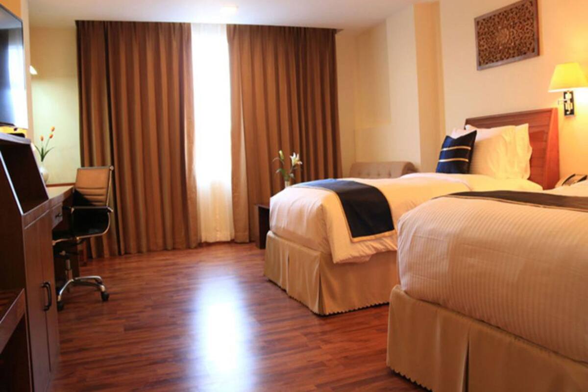A hotel room with two beds, a desk, and a chair.