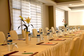 A conference room with a long table, chairs, water bottles, and a vase with flowers.