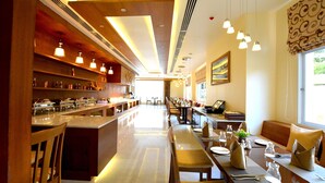 A spacious hotel dining area with a long counter, multiple tables, and a variety of seating options. - Eastern Palace Hotel (Mandalay)