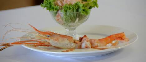A plate with a cooked lobster and a glass bowl containing salad.