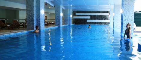 An indoor swimming pool with tiled walls and a clear blue pool.