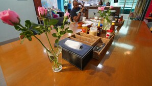 Ein Holztisch mit einer Papiertuchbox, einer Vase mit einer Rose und verschiedenen Gewürzen.
