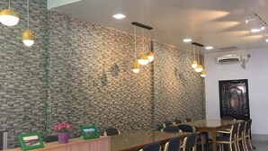 Ein Konferenzraum mit einem langen Holztisch, mehreren Stühlen, einem Empfangstresen und einer Wand aus strukturiertem Stein.