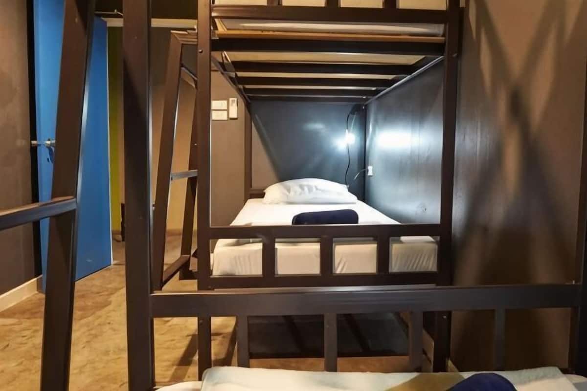 A bunk bed room with a wooden frame, a single bed, and a door.