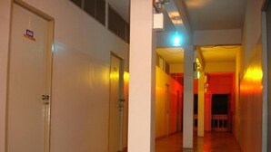 Corredor de hotel com porta identificada com o número 410 e um hall bem iluminado com parede em tom avermelhado.