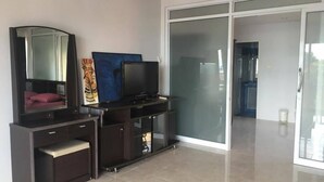 Un saló modern amb una televisió plana, un mirall gran i un quadre a la paret.