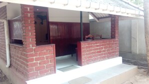 A small brick building with a covered porch, a door, and a window. - Sarathchandra Tourist Guest House (Embilipitiya)
